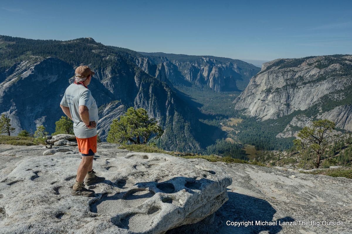 A hiker on North Dome overlooking Yosemite Valley in Yosemite National Park.