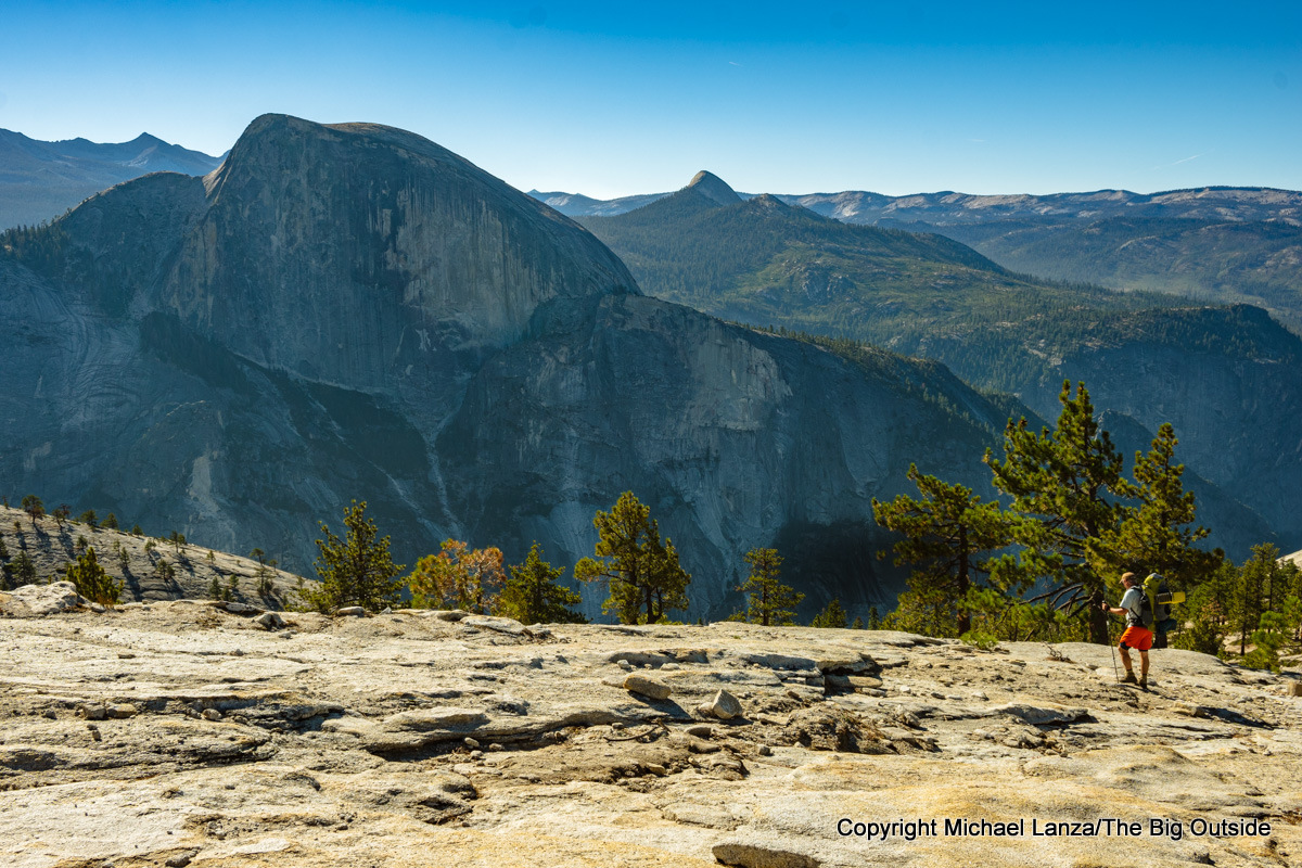 A backpacker hiking Indian Ridge, overlooking Half Dome in Yosemite National Park.