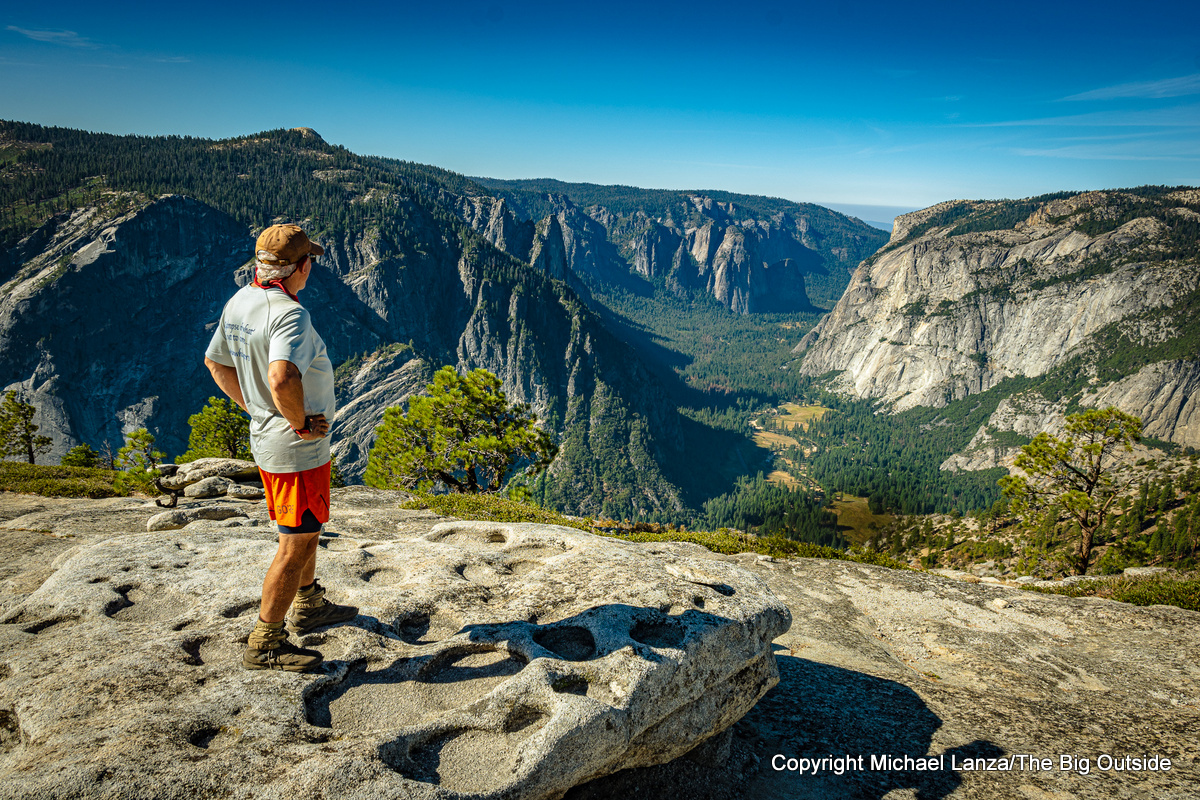 A hiker on North Dome, overlooking Yosemite Valley in Yosemite National Park.