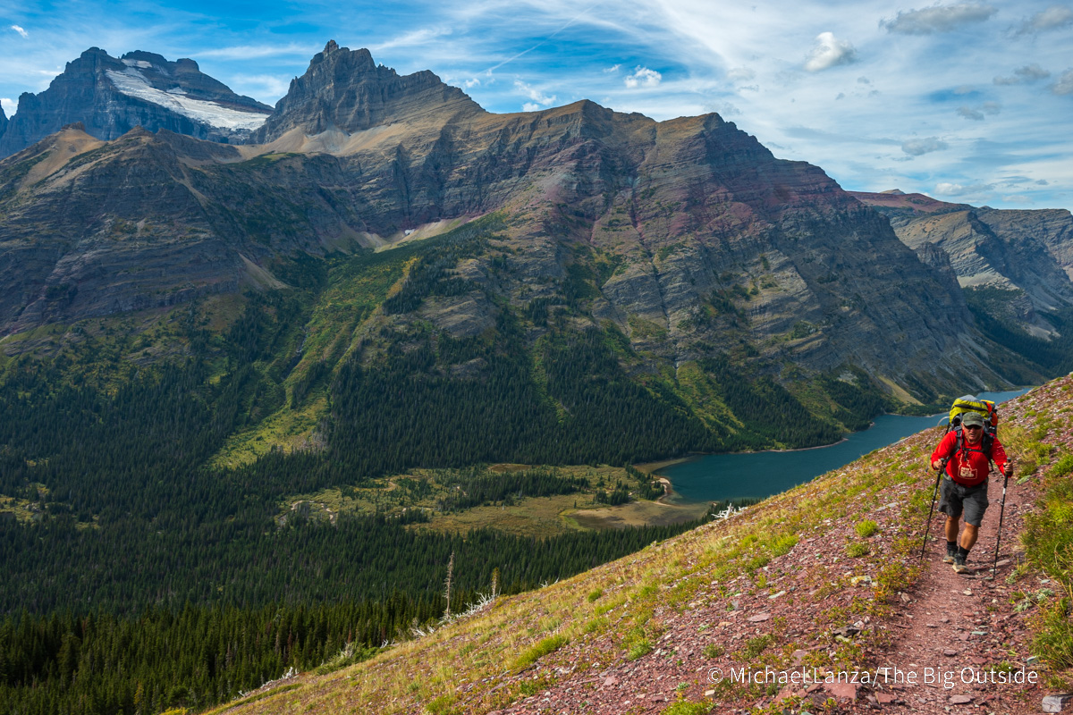 A backpacker hiking the Ptarmigan Tunnel Trail above Elizabeth Lake in Glacier National Park.