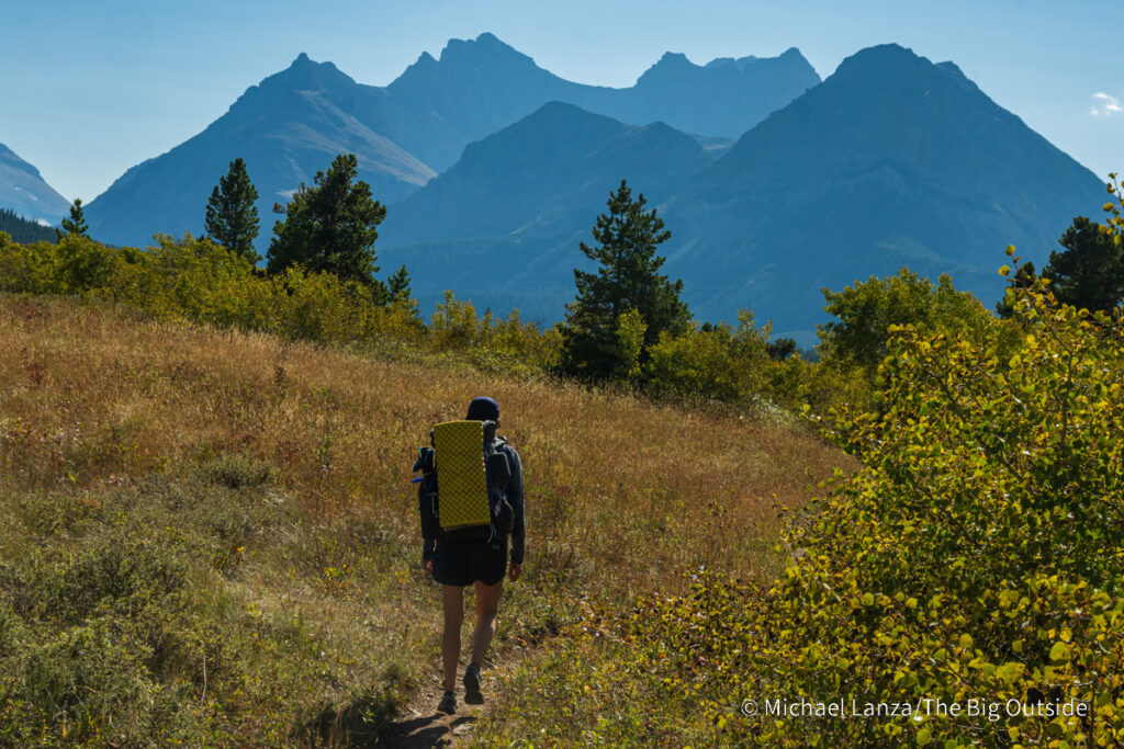 A backpacker hiking up the Belly River Valley in Glacier National Park. A backpacker hiking up the Belly River Valley in Glacier National Park.