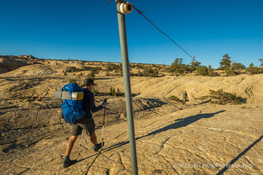 A backpacker hiking the Boulder Mail Trail past the old telegraph line in Utah's Grand Staircase-Escalante National Monument. A backpacker hiking the Boulder Mail Trail past the old telegraph line in Utah's Grand Staircase-Escalante National Monument.