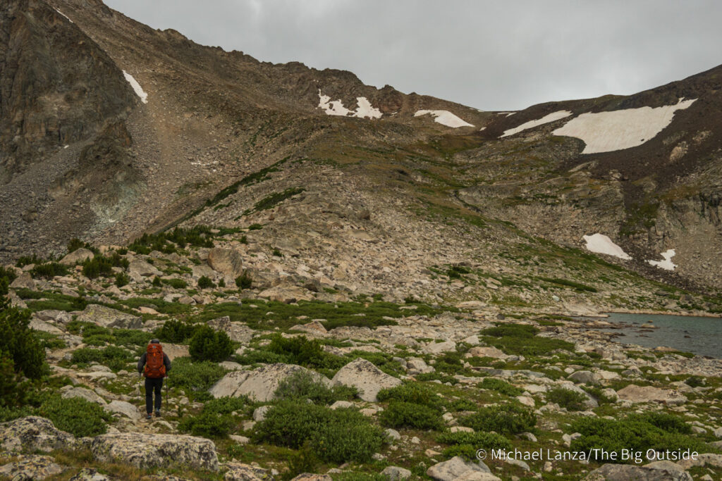 A backpacker hiking toward Washakie Pass in the Wind River Range, Wyoming. A backpacker hiking toward Washakie Pass in the Wind River Range, Wyoming.