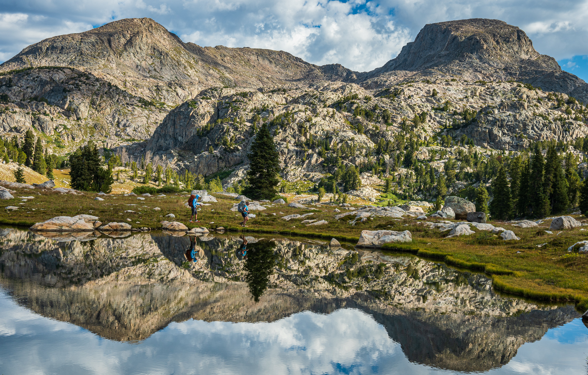Backpackers passing a small tarn just off the Highline Trail in the Wind River Range.