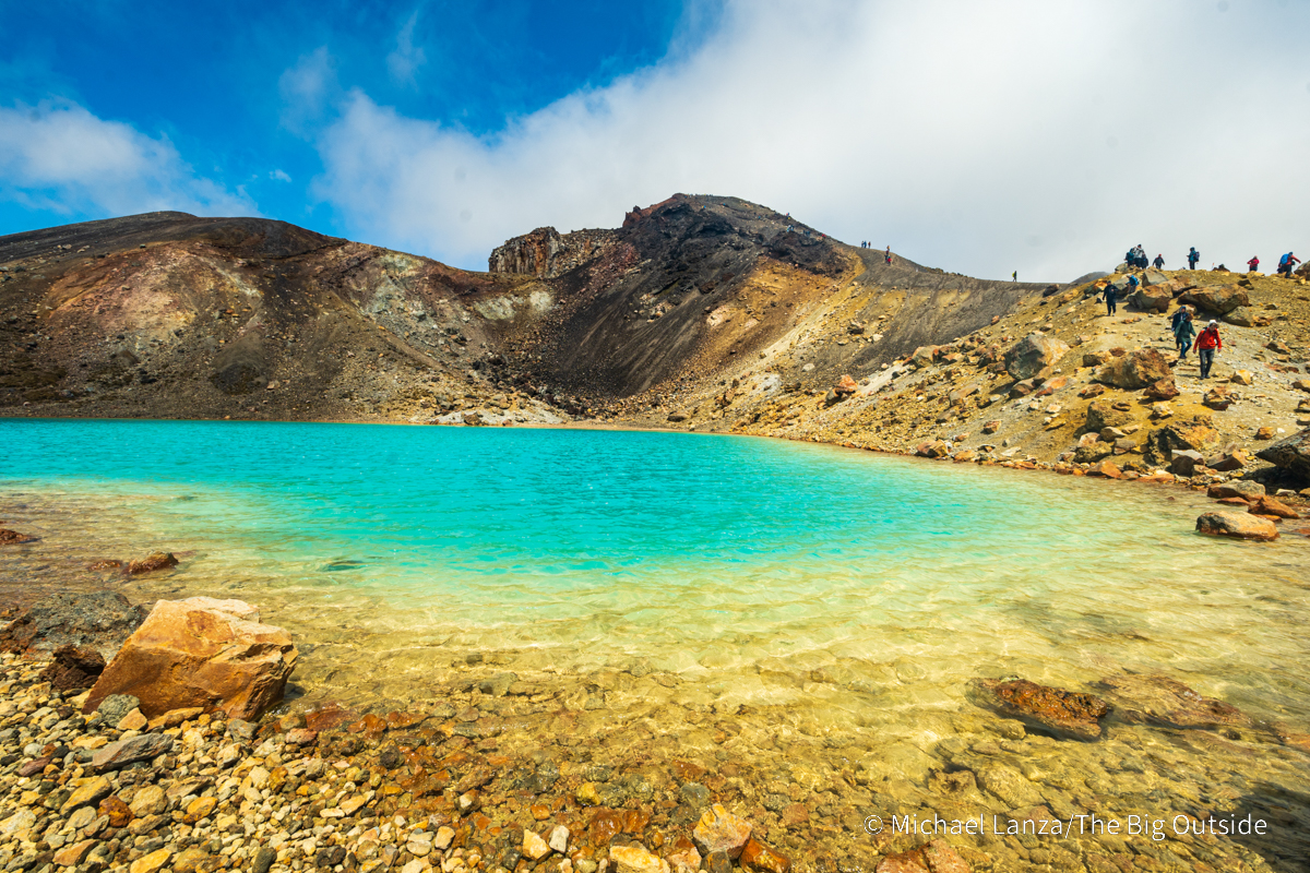 Hikers passing the largest of the three Emerald Lakes along the Tongariro Alpine Crossing, North Island, New Zealand.